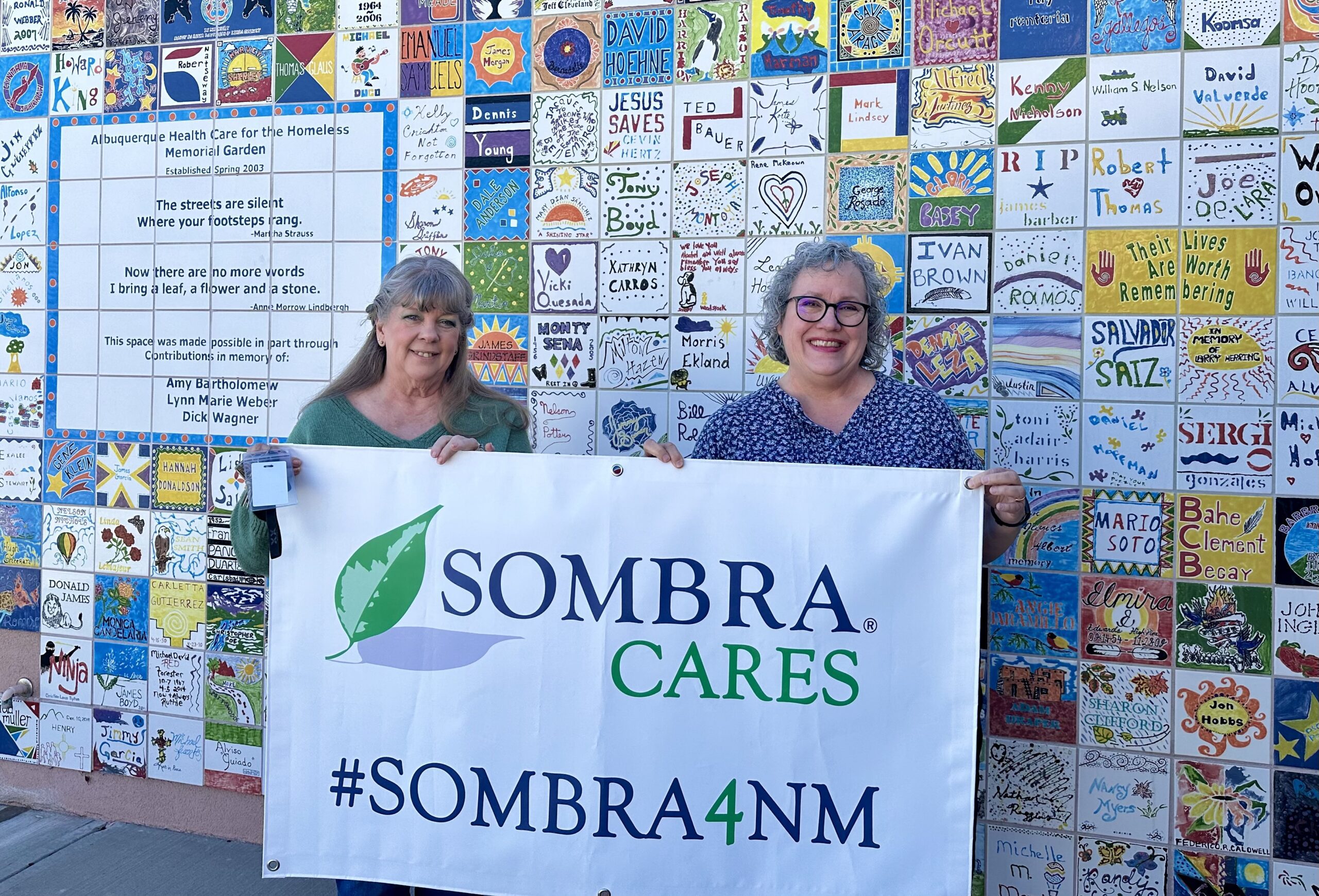 Image of two ladies holding a Sombra Cares banner